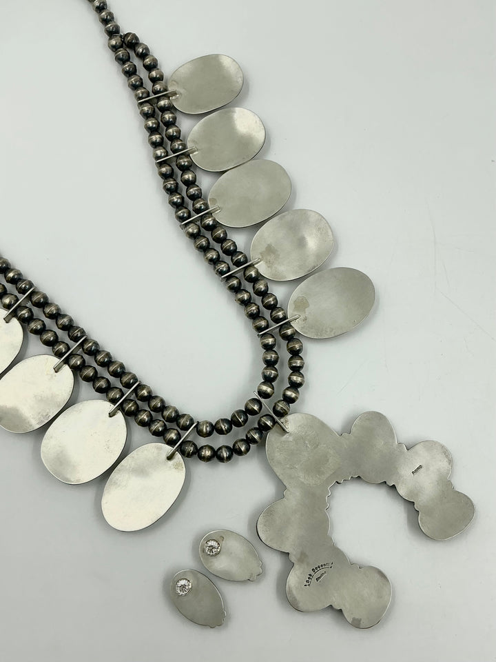 Back of set with necklace, earrings, and Naja pendant showing stamped silver on a light gray background. 