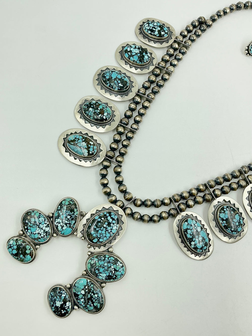 Jewelry set with necklace, earrings, and Naja pendant on a light gray background