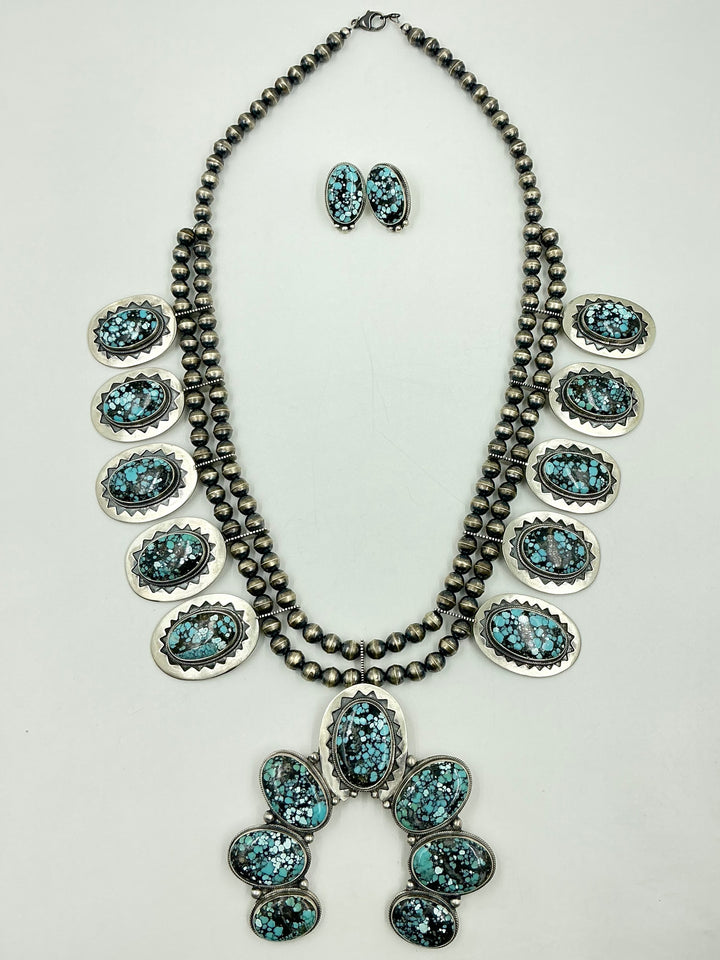 Jewelry set with necklace, earrings, and Naja pendant on a light gray background