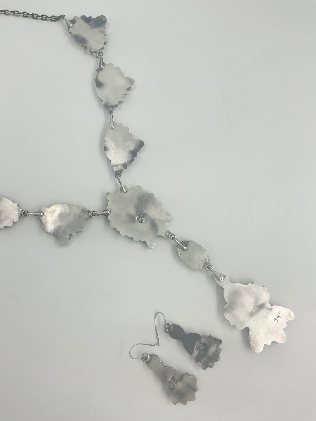 Silver back of Y shaped necklace and earrings set with green and turquoise stone clusters set on sterling silver showing stamped silver on a white background