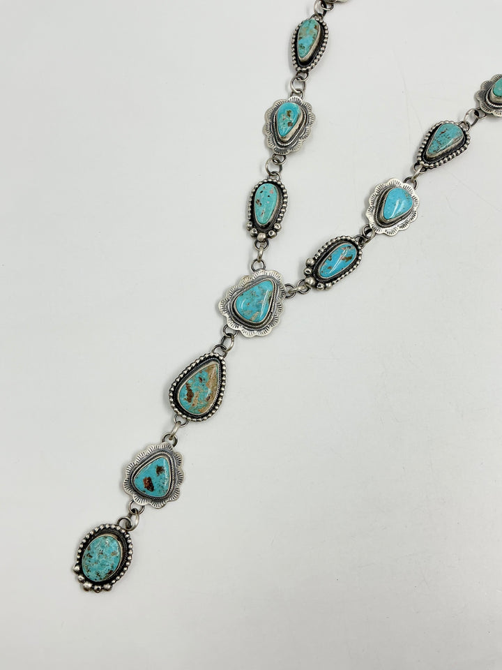  Y shaped Necklace turquoise stones set in sterling silver with accents on a white background with earrings. 