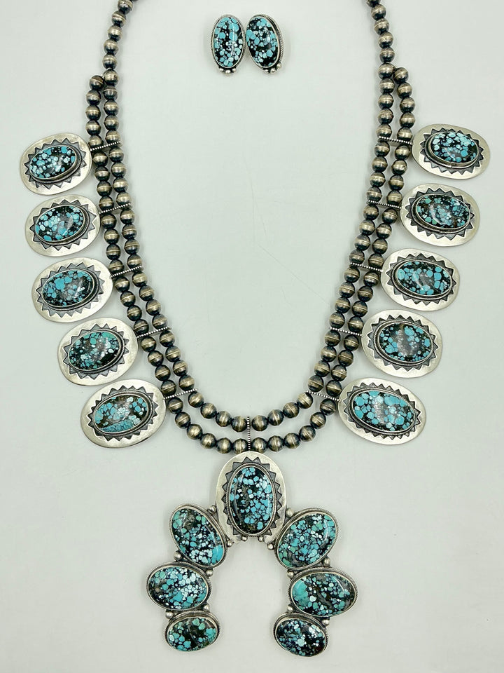 Jewelry set with necklace, earrings, and Naja pendant on a light gray background