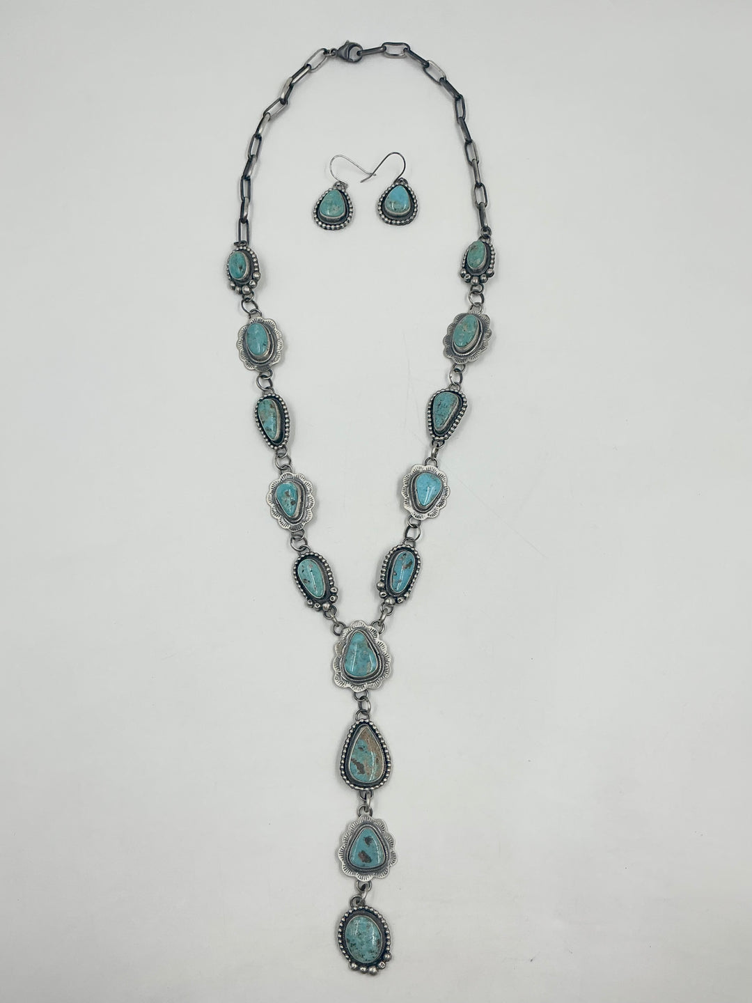  Y shaped Necklace turquoise stones set in sterling silver with accents on a white background with earrings. 