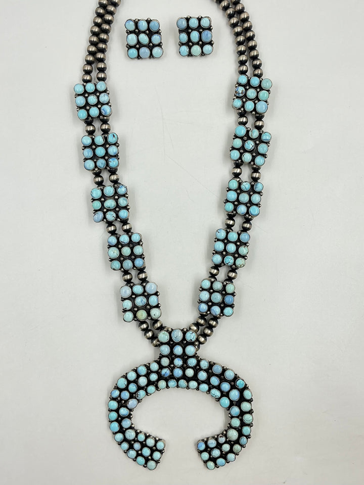 Golden Hills turquoise necklace and earrings set with light blue and lavender colored stones set in sterling silver with small cluster square formations on a white background. 