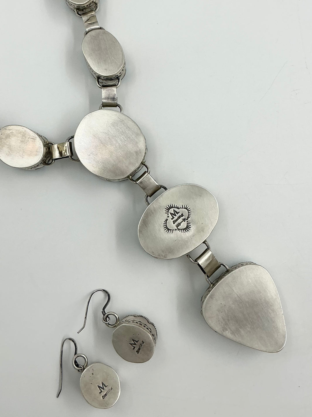 Silver back pf Y shaped Necklace with blue, green and gold gemstones set in sterling silver with accents on a white background showing stamped silver. 