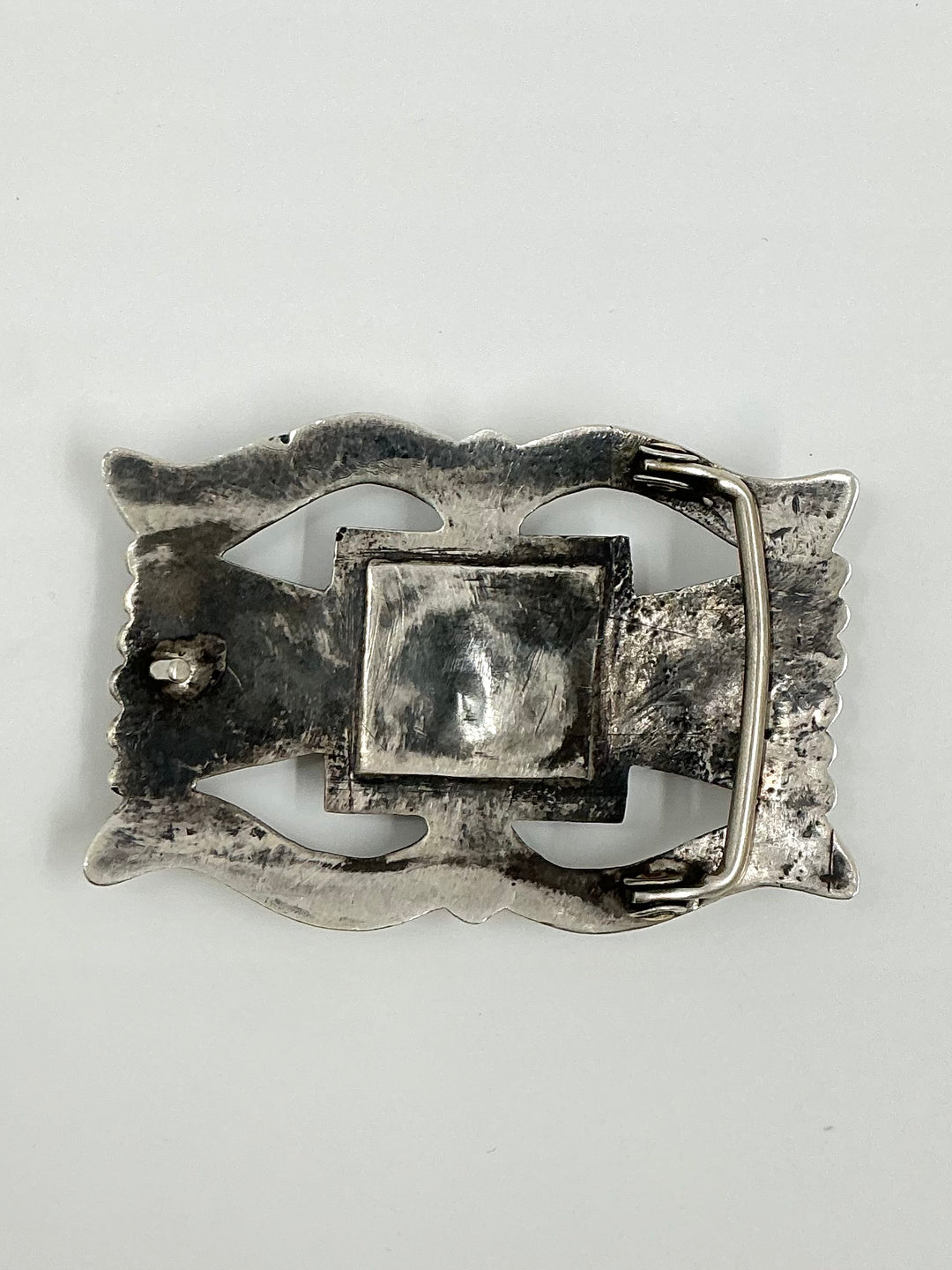 Silver belt buckle on a light gray background
