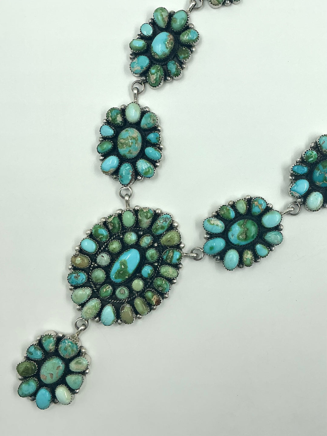 Y shaped Necklace with small green and blue gemstone clusters and set in round flower like sterling silver on a white background