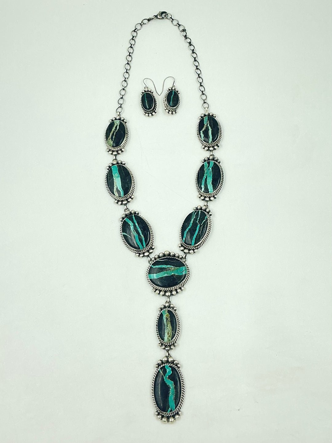 Y shaped Necklace with black and green gemstones set in sterling silver with accents on a white background