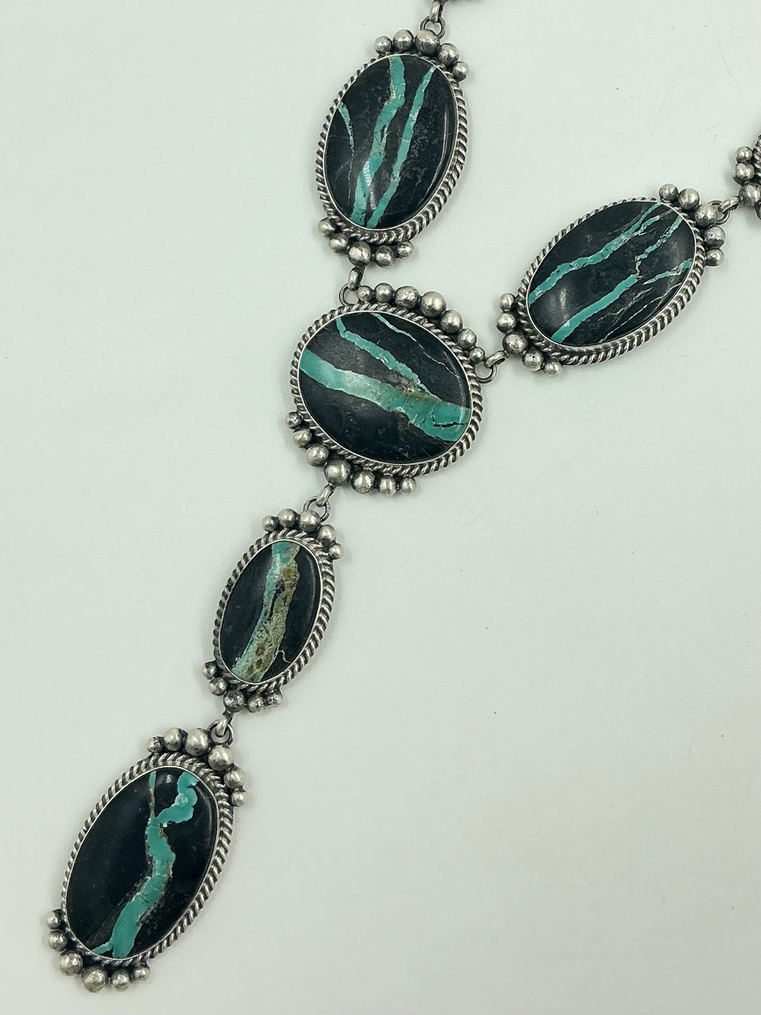 Y shaped Necklace with black and green gemstones set in sterling silver with accents on a white background