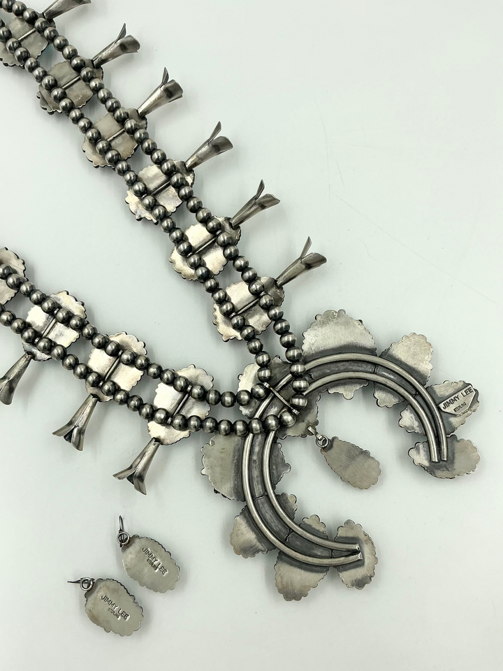 Silver back of turquoise stone necklace on sterling silver with leaf accents and earrings on a light gray background
