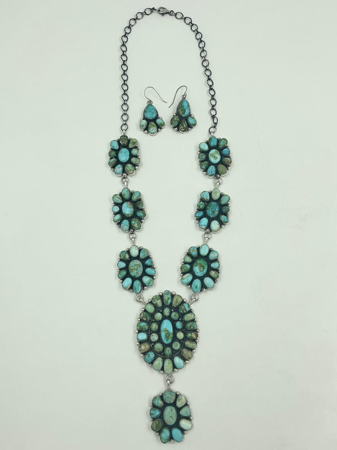 Y shaped Necklace with small green and blue gemstone clusters and set in round flower like sterling silver on a white background